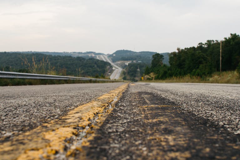 Close-up view of a rural road on a summer day, winding through lush green hills.